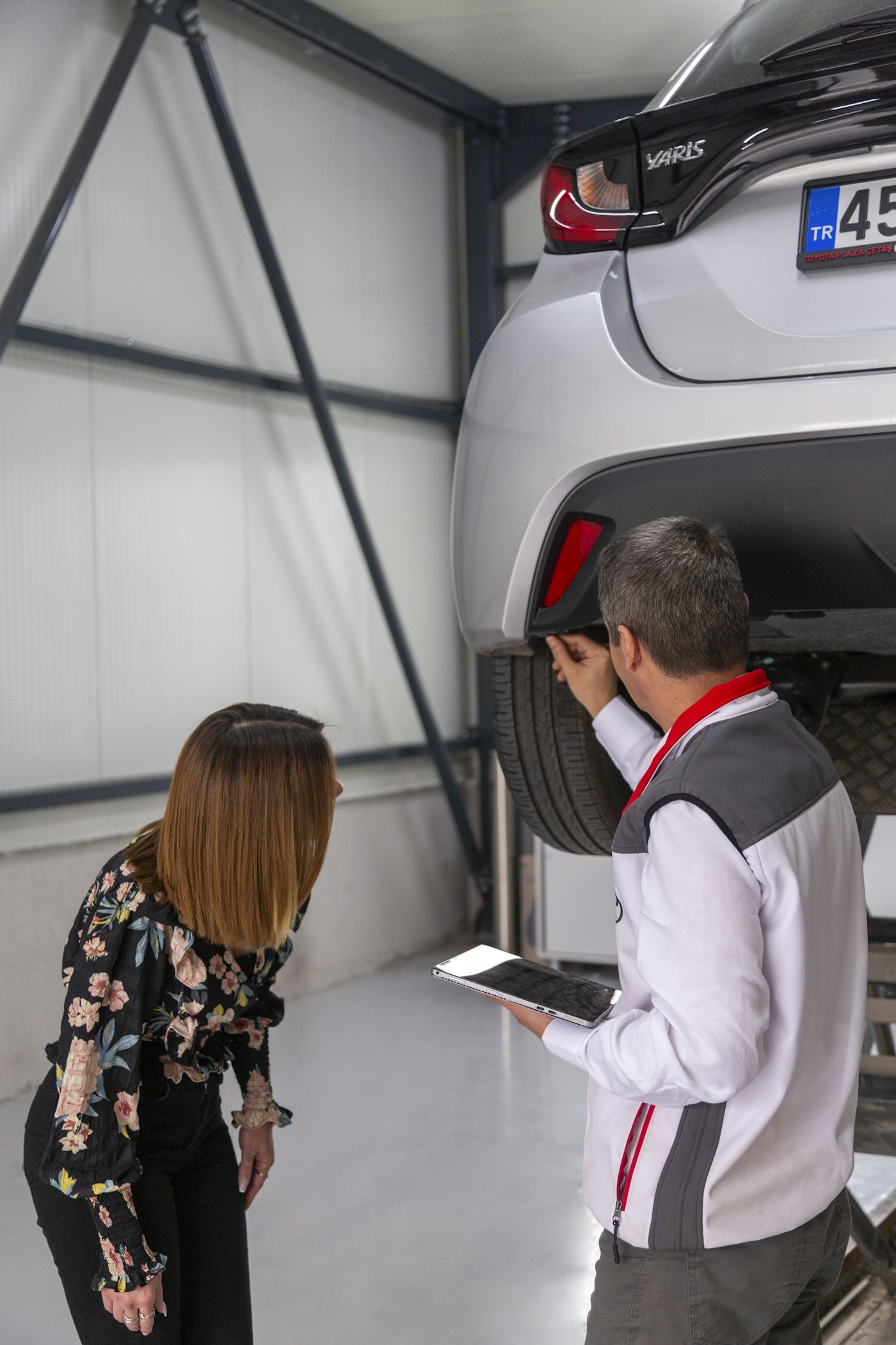 Dos técnicos revisando los bajos de un coche elevado en el taller
